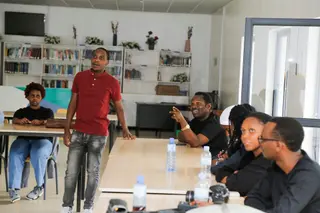 Youssouf Hakizimana speaking to a diverse group of people seated at tables