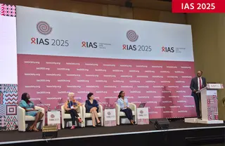 Panel discussion at IAS 2025 conference with a speaker at the lectern and four panelists on stage under event branding.